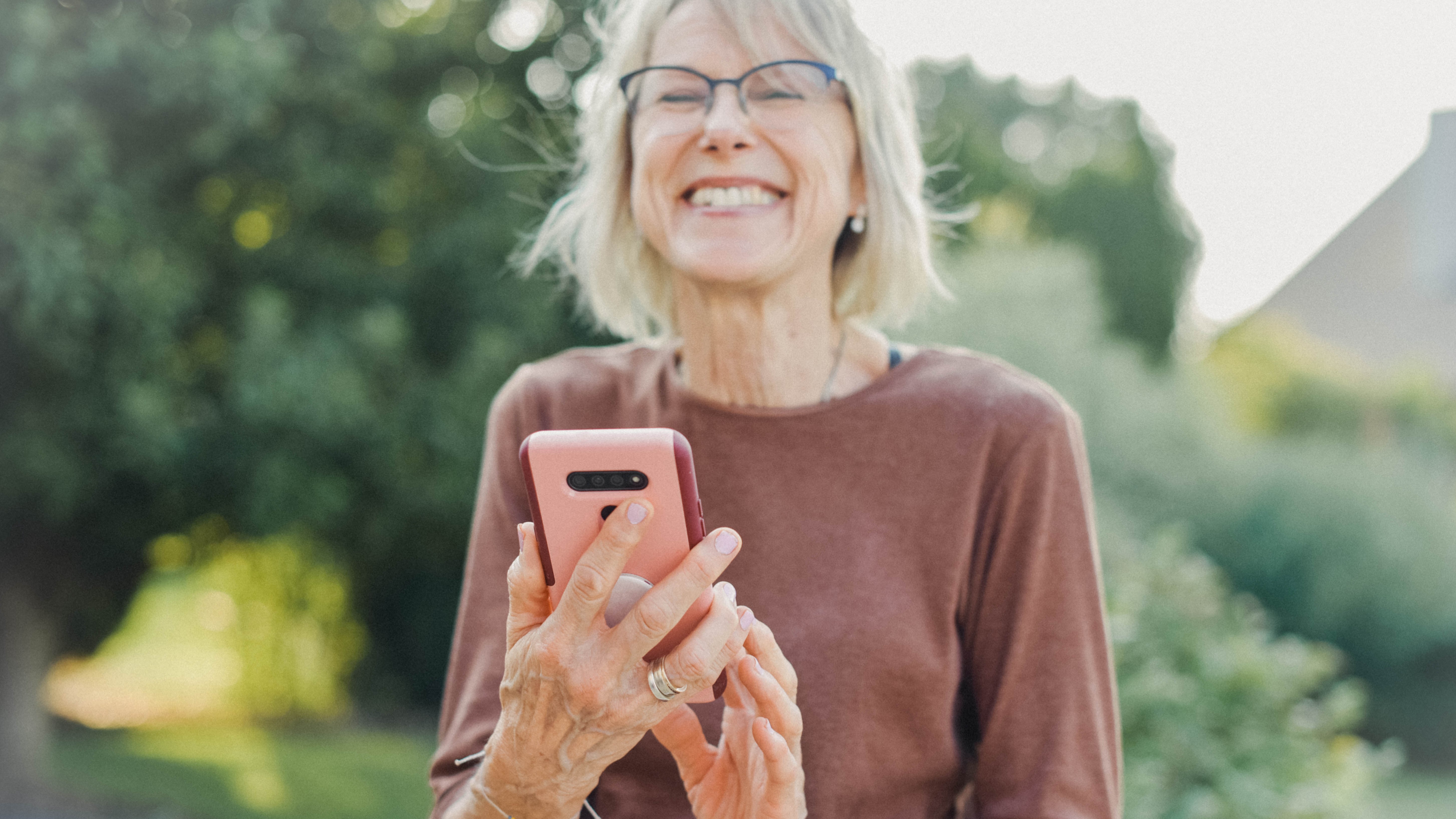 glückliche Ältere Frau mit Smartphone in der Hand