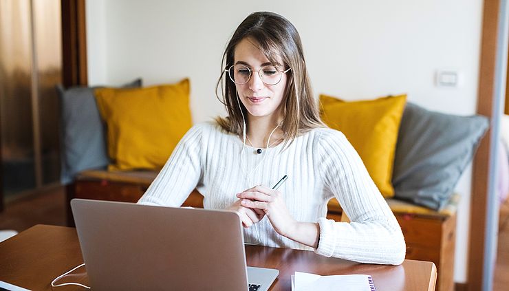 junge Frau sieht sich ein Webinar am Laptop an