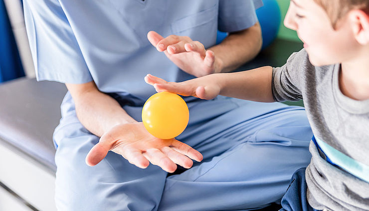 Ergotherapeutin macht Ballünbungen mit kleinem Jungen
