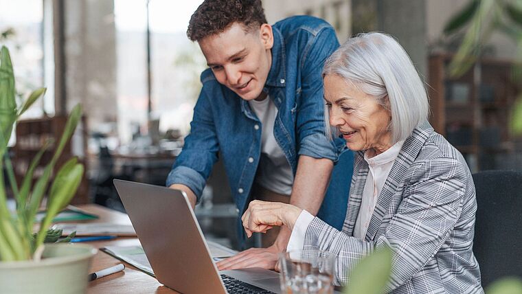 ältere Frau und junger Mann vor einem Laptop