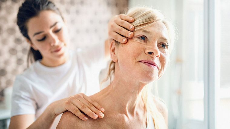 Therapeutin behandelt den Nacken einer Seniorin